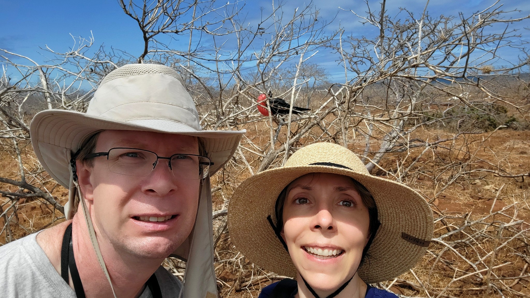 Erik and Michelle Anderson in the Galápagos Islands with a frigatebird perched in the background